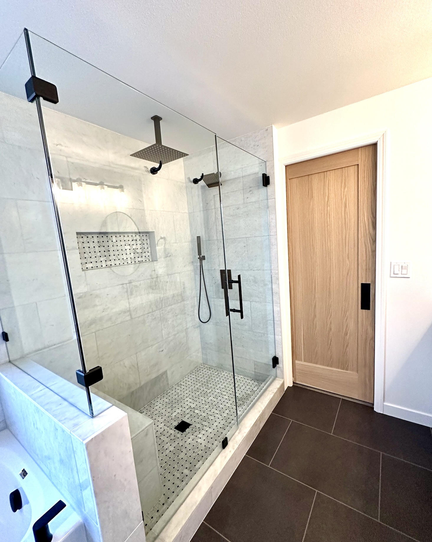 Bright and clean newly remodeled primary shower, with two glass walls and natural tile stone on walls and floor